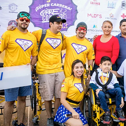 Voluntarios disfrazados de superhéroes acompañan a un niño en silla de ruedas en la meta